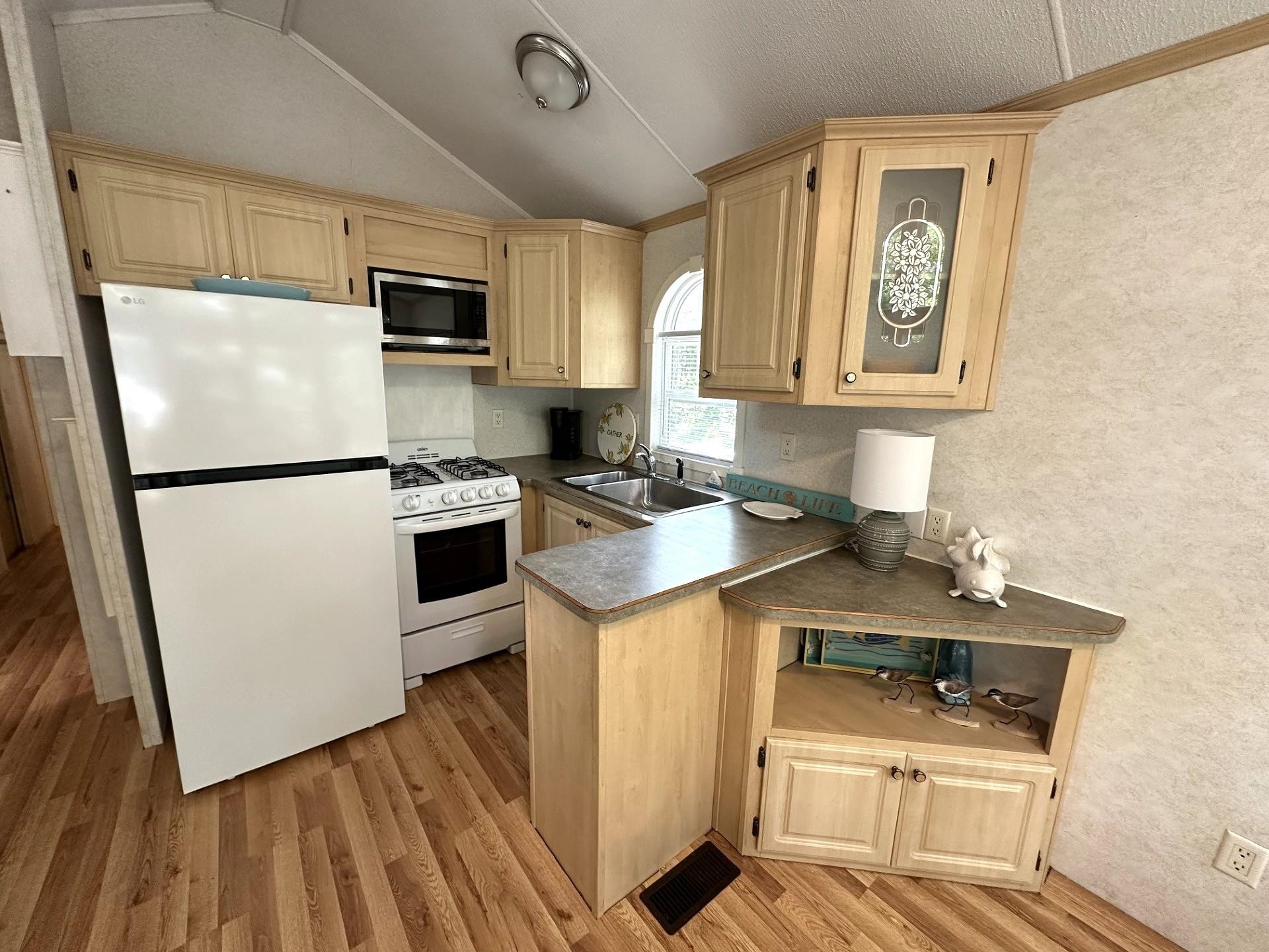 3066 North Rte 9 Ocean View, NJ 08230 - Photo 17 of 49 a kitchen with a refrigerator a stove top oven a sink and dishwasher with wooden floor