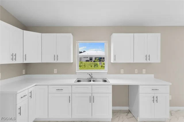 a kitchen with white cabinets and sink