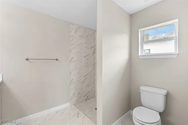 a white toilet sitting next to a shower