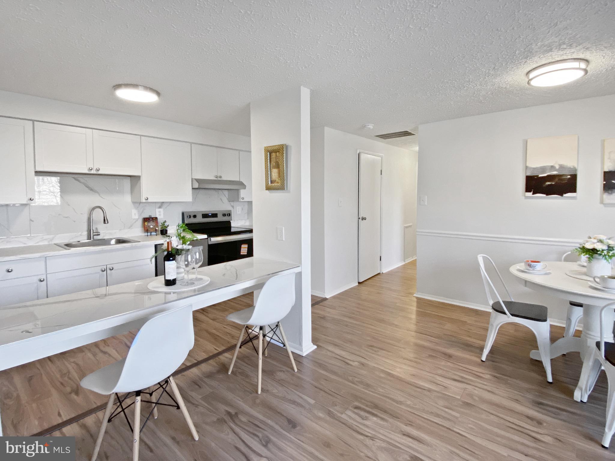 19525 Gunners Branch Road, Unit 222 Germantown, MD 20876 - Photo 13 of 15 a kitchen with stainless steel appliances wooden floor and chairs