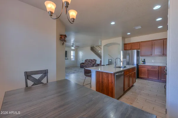 a kitchen with stainless steel appliances kitchen island granite countertop a sink a stove a refrigerator with a dining table and chairs