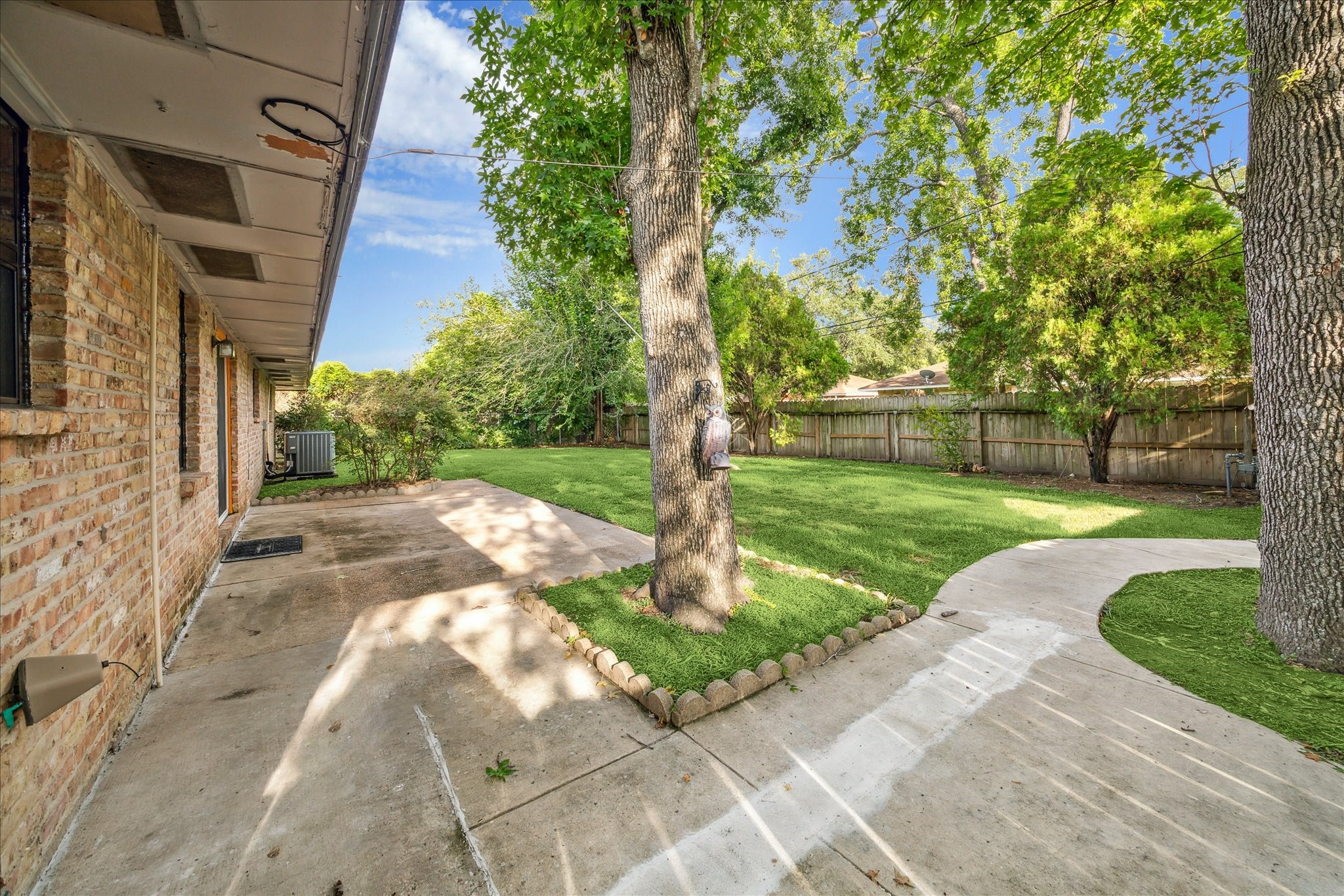 8907 Autauga Street Houston, TX 77080 - Photo 18 of 20 This spacious backyard features mature trees providing shade, and a paved patio area adjacent to the brick exterior of the house. A curved walkway leads through the yard, adding charm and functionality. Ideal for outdoor activities and relaxation.