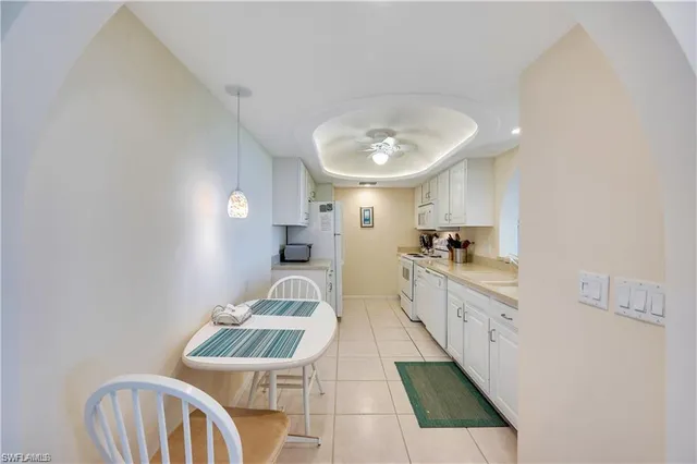 a large white kitchen with a sink stainless steel appliances and a chandelier