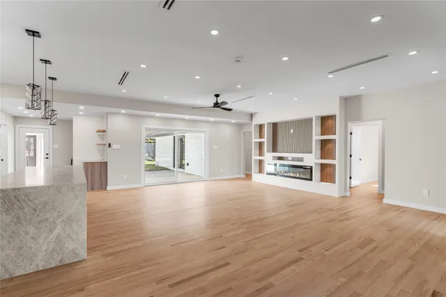 a view of an empty room with wooden floor and kitchen
