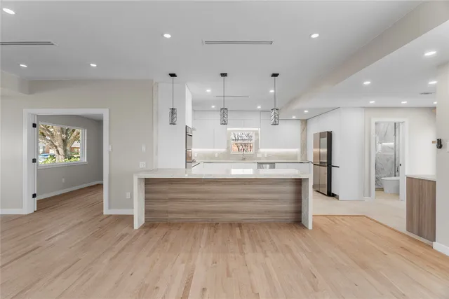 a large kitchen with stainless steel appliances a large counter top a stove and a refrigerator