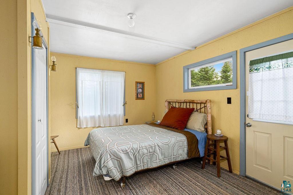1268 Tom Lake Road Hovland, MN 55606 - Photo 24 of 56 Bedroom featuring yellow-painted walls, a striped carpet, and a window with white sheers