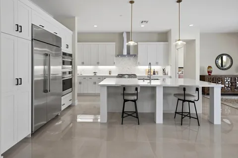 a kitchen with stainless steel appliances kitchen island granite countertop a table chairs refrigerator and microwave