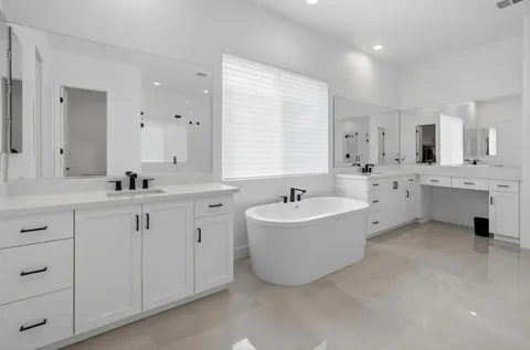a spacious bathroom with a double vanity sink mirror and bathtub
