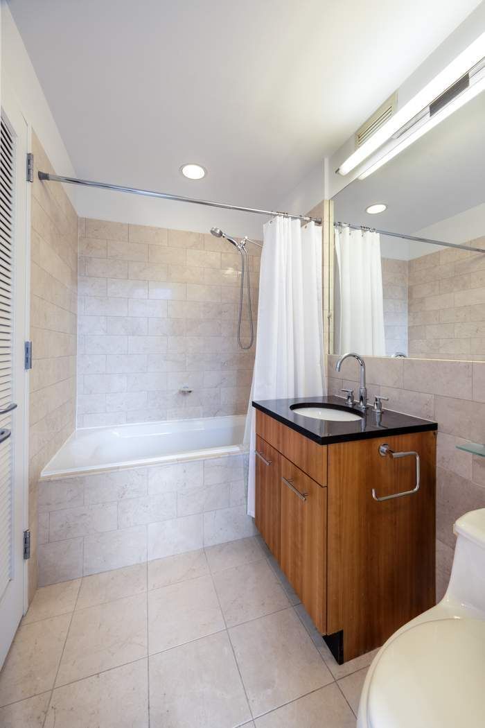 11 East 29th Street, Unit 16B Manhattan, NY 10016 - Photo 4 of 6 a bathroom with a granite countertop bathtub sink vanity and mirror