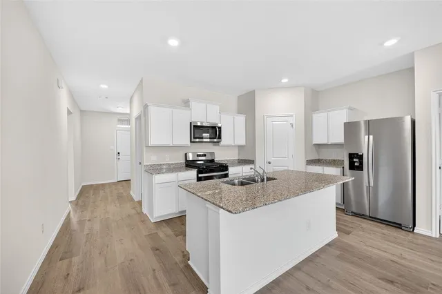 a kitchen with stainless steel appliances granite countertop a sink stove refrigerator and cabinets