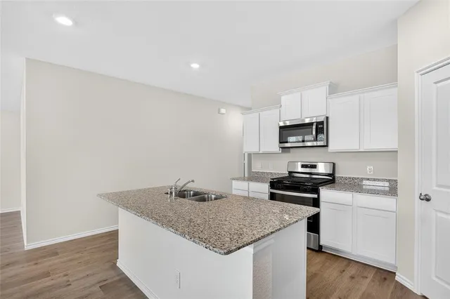a kitchen with granite countertop a sink stove and microwave
