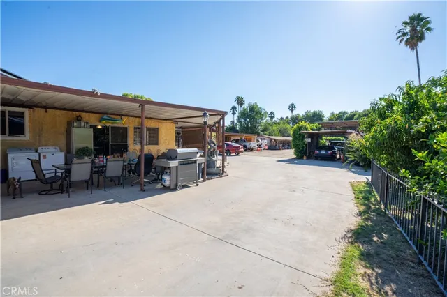 a view of a patio with table and chairs potted plants and a large tree