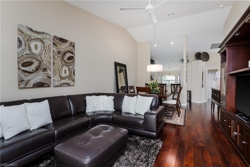 6658 Castlelawn Place, Unit 9 Naples, FL 34113 - Photo 14 of 38 Living area featuring wood-finish flooring, a built-in media cabinet, and a vaulted ceiling