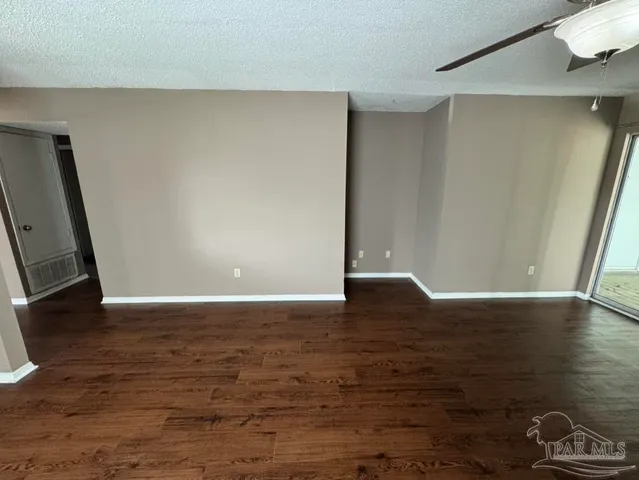 a view of an empty room with wooden floor fireplace and a window
