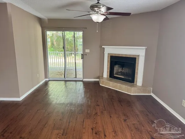 a view of an empty room with wooden floor and a fireplace