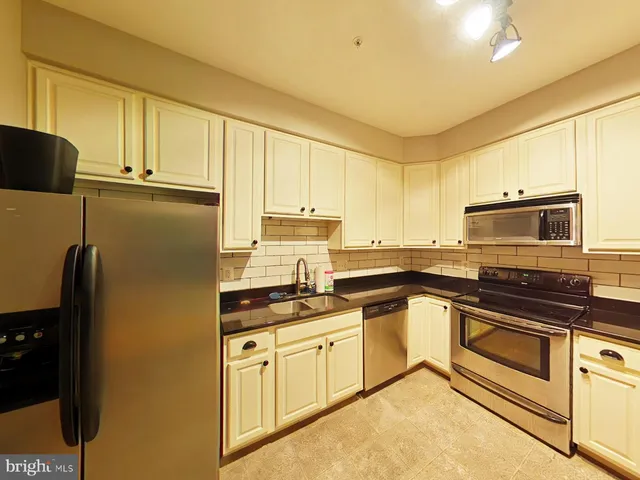 a kitchen with stainless steel appliances granite countertop a refrigerator a stove and white cabinets