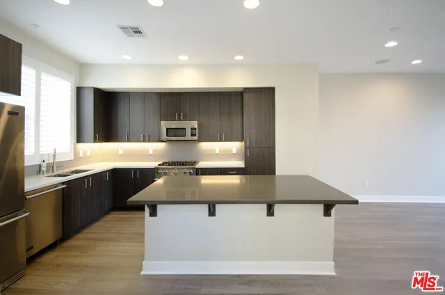 a kitchen with kitchen island granite countertop a sink a stove and refrigerator