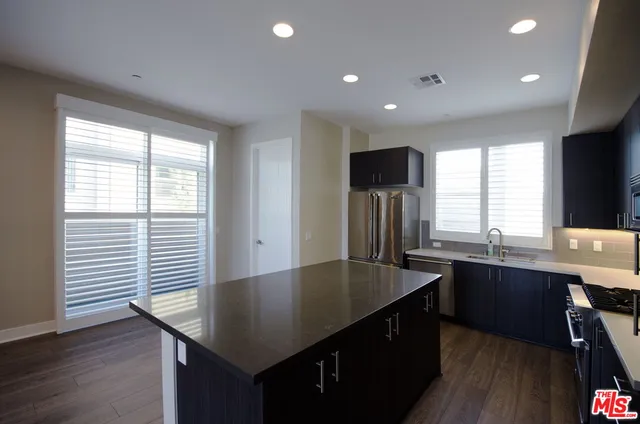 a kitchen with stainless steel appliances granite countertop a sink a window and wooden floor
