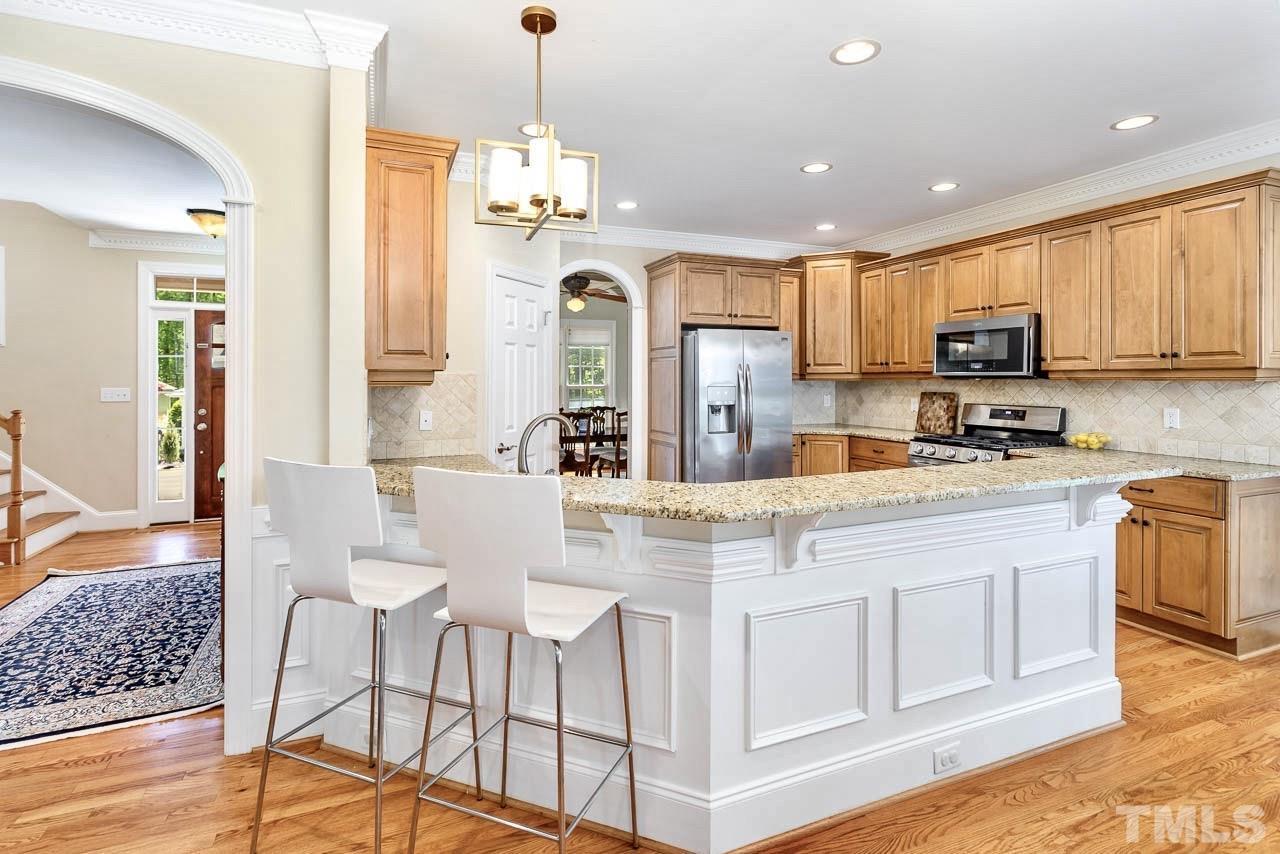 8333 Wheatstone Lane Raleigh, NC 27613 - Photo 9 of 34 a kitchen with stainless steel appliances granite countertop a refrigerator a stove a sink dishwasher and white cabinets with wooden floor