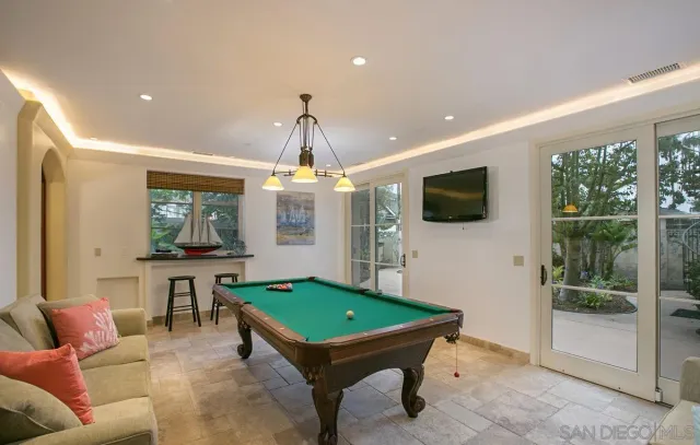 a room with furniture pool table flat screen tv and windows