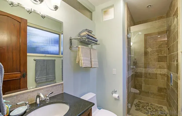 a bathroom with a granite countertop sink a mirror and a shower