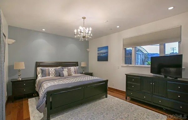 a bedroom with a bed and a flat tv screen on dresser
