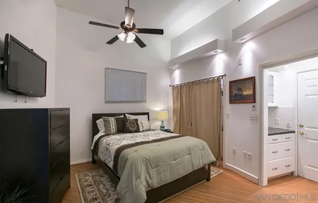 a bedroom with a bed and a flat tv screen on the dresser