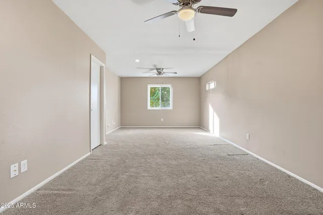 en empty room with windows and chandelier fan