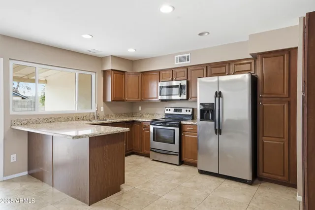 a kitchen with stainless steel appliances granite countertop a refrigerator a stove a sink and a refrigerator