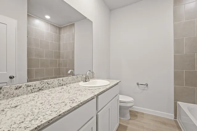a bathroom with a granite countertop sink a toilet and a mirror