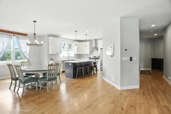 a kitchen with stainless steel appliances a dining table chairs a sink and a refrigerator
