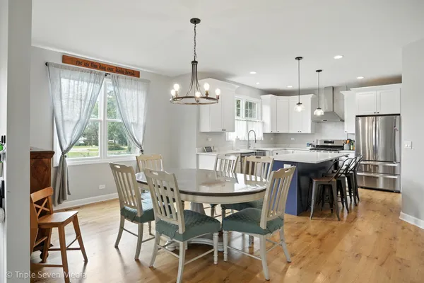 a kitchen with kitchen island a dining table chairs and white cabinets