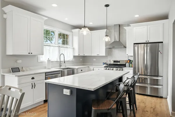 a kitchen with stainless steel appliances granite countertop a refrigerator a sink a stove a dining table and chairs