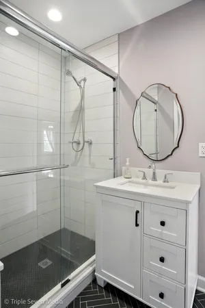 a bathroom with a granite countertop sink a mirror and shower