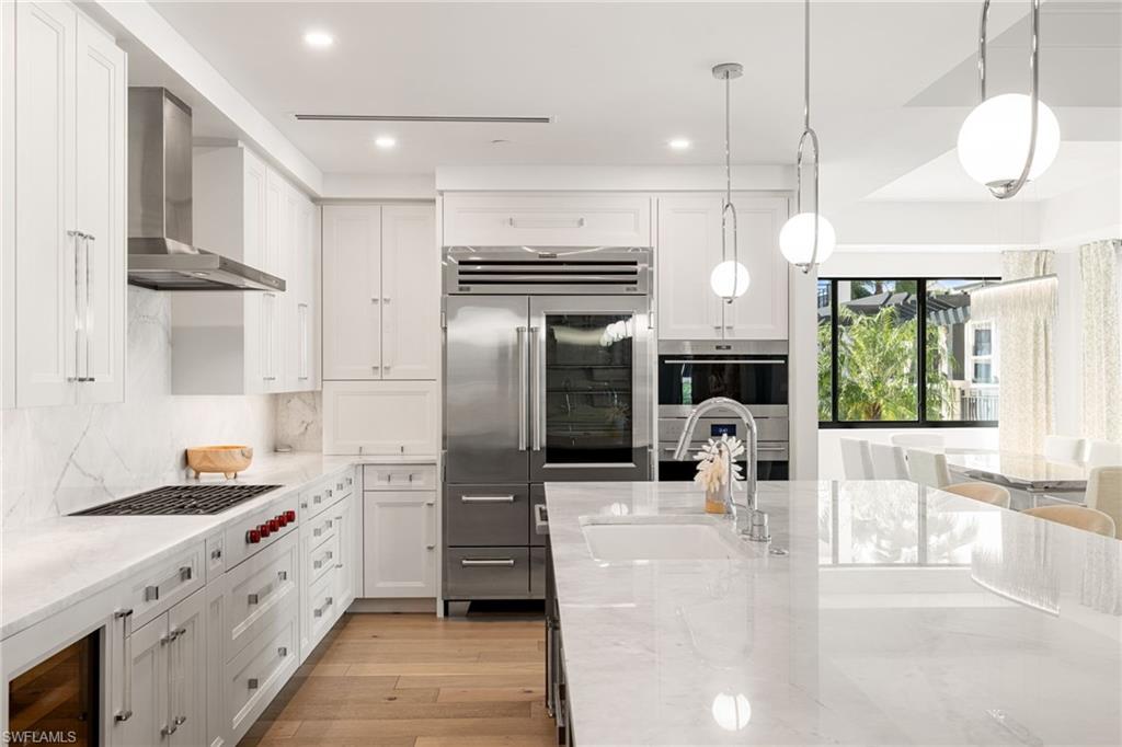 1130 3rd Avenue South, Unit 210 Naples, FL 34102 - Photo 12 of 48 a kitchen with stainless steel appliances kitchen island granite countertop a refrigerator a oven a stove and a sink with granite countertops
