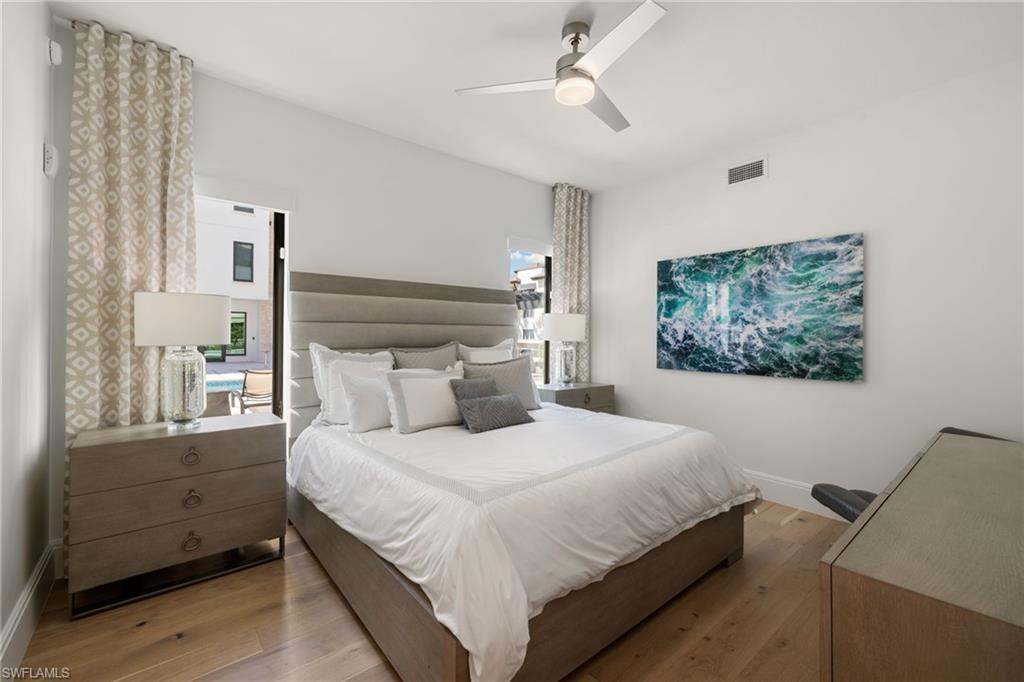 1130 3rd Avenue South, Unit 210 Naples, FL 34102 - Photo 24 of 48 a bedroom with a large bed and a chandelier