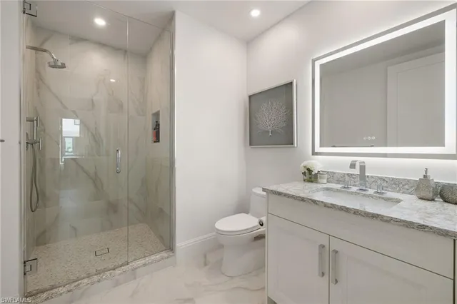 a bathroom with a granite countertop sink a toilet a mirror and shower