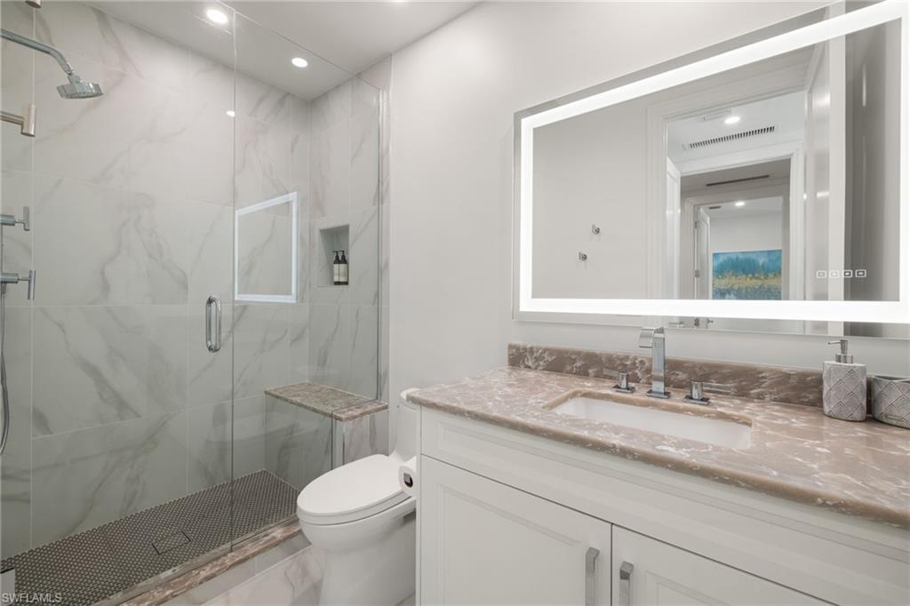 1130 3rd Avenue South, Unit 210 Naples, FL 34102 - Photo 30 of 48 a bathroom with a granite countertop toilet sink shower and mirror