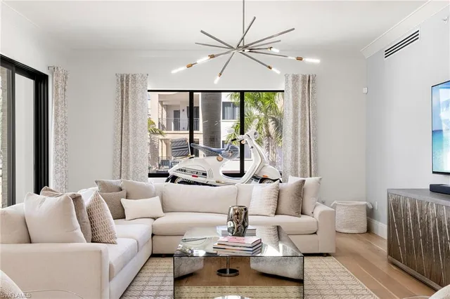a living room with furniture a large window and a chandelier