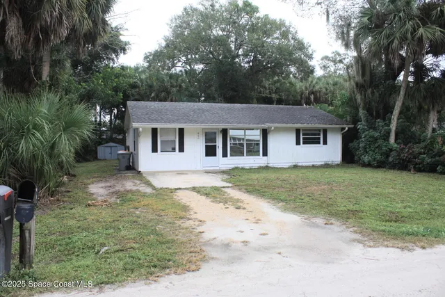 a view of a yard in front of a house with large trees