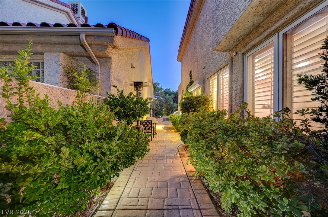 7995 Rio Rico Drive Las Vegas, NV 89113 - Photo 60 of 92 An inviting stone pathway guides visitors between two stucco-finished buildings, illuminated by evening lights.