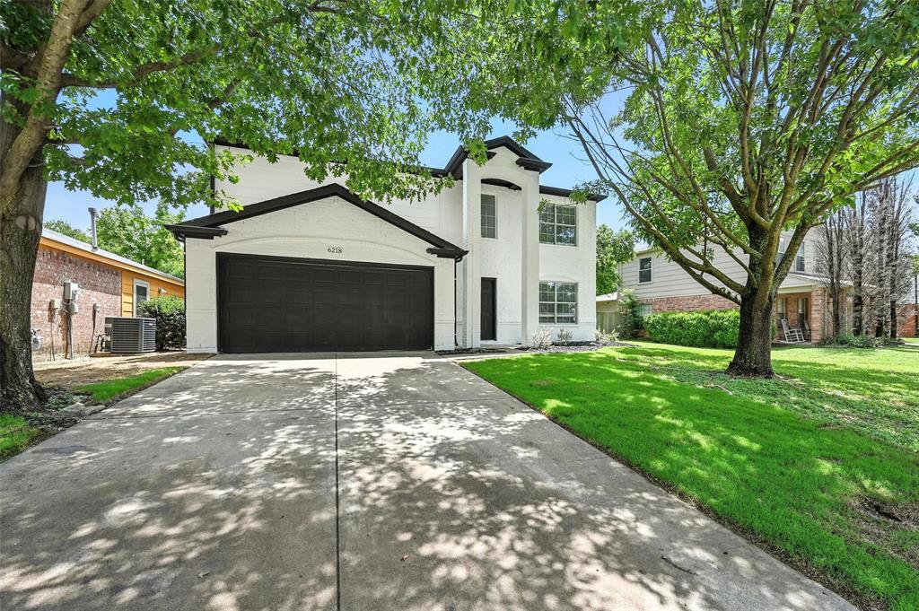 View of front of home featuring a garage, a front yard, driveway, and stucco siding