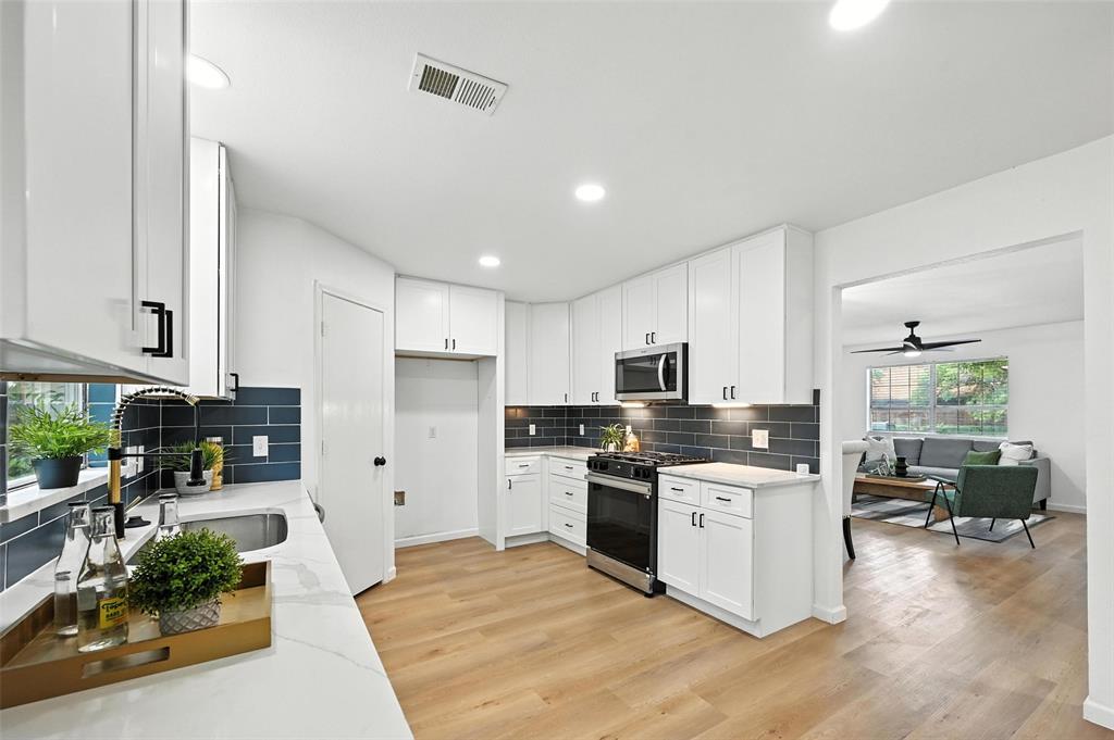 6218 Everglade Road Dallas, TX 75227 - Photo 8 of 39 Kitchen with gas range oven, stainless steel microwave, light wood finished floors, backsplash, and recessed lighting