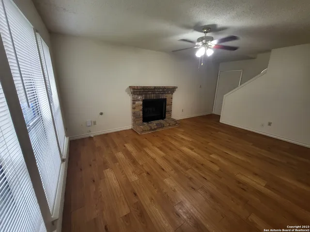 a view of an empty room with wooden floor and a chandelier