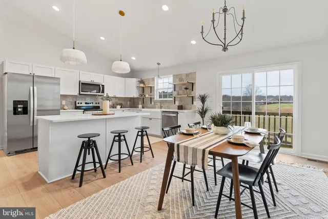 a kitchen with stainless steel appliances a stove a sink refrigerator and a dining table with wooden floor