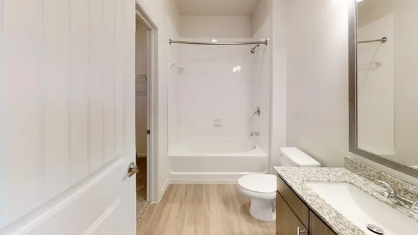 a bathroom with a granite countertop bathtub sink vanity mirror and toilet