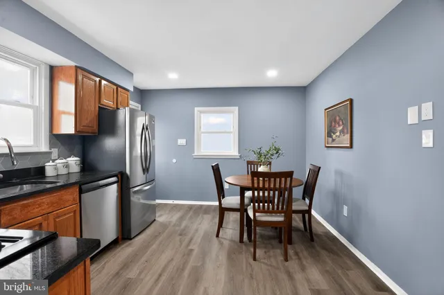 a kitchen with stainless steel appliances granite countertop a dining table chairs refrigerator and sink