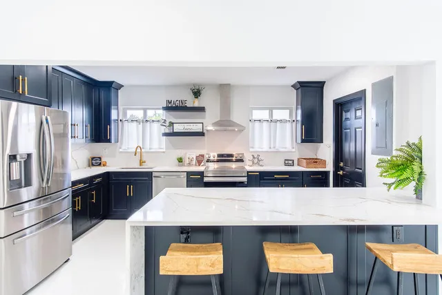 a kitchen with stainless steel appliances kitchen island granite countertop a refrigerator a stove and a sink with wooden floor