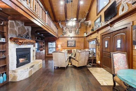 a living room with couches a fireplace and a dining table with wooden floor