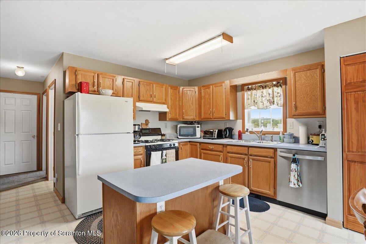 5231 Fiddle Lake Road Thompson, PA 18465 - Photo 10 of 34 a kitchen with stainless steel appliances granite countertop a refrigerator a stove top oven a sink dishwasher and white cabinets